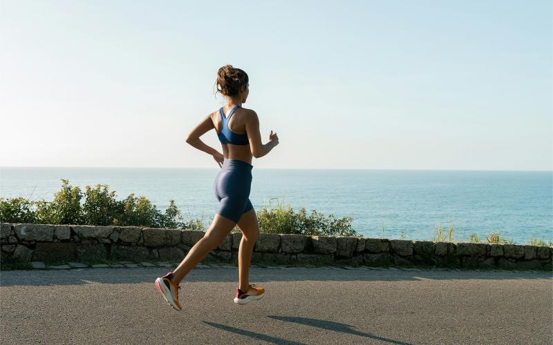 a woman running on a road by the water